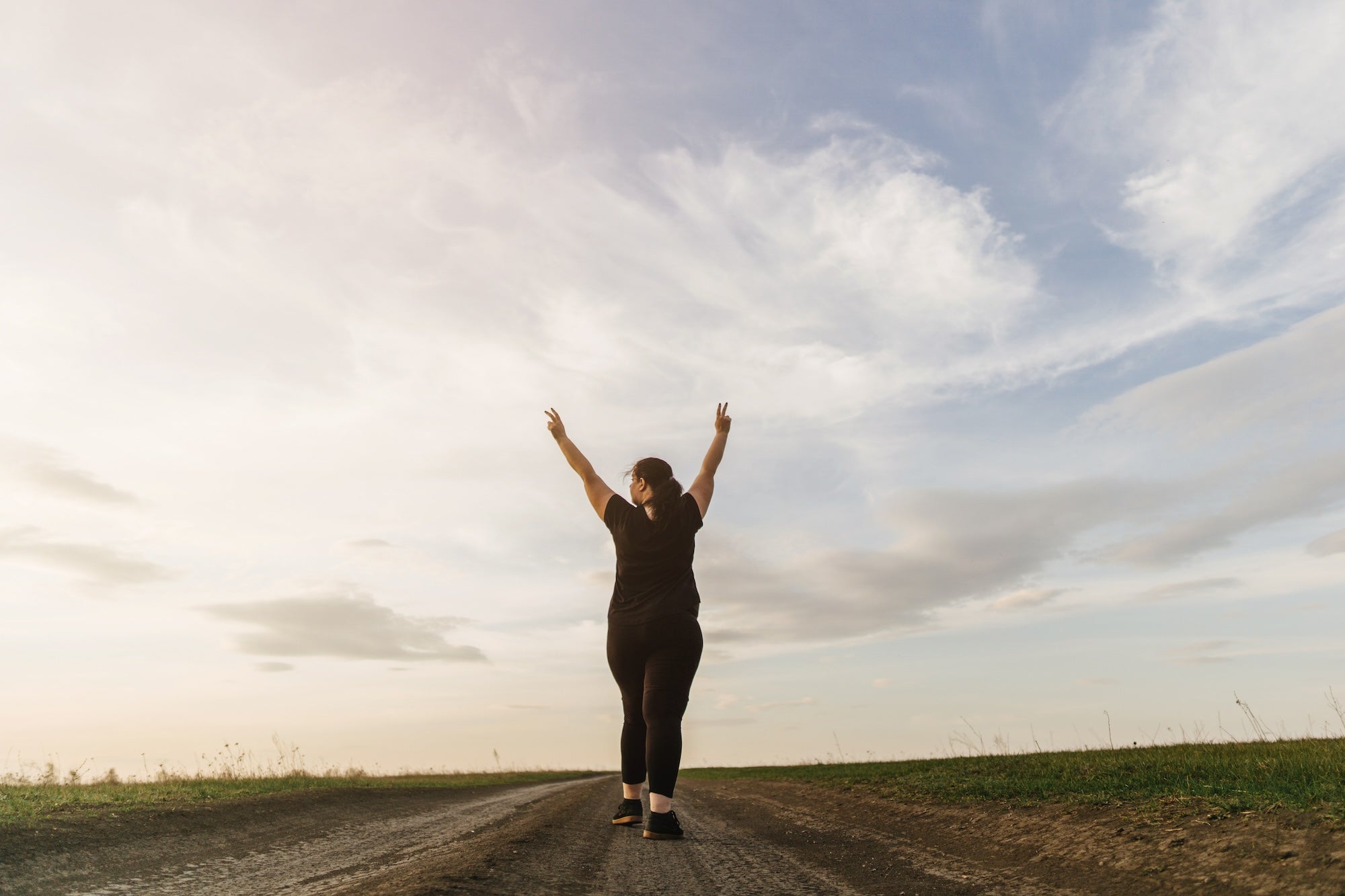Woman walking along a path with arms raised